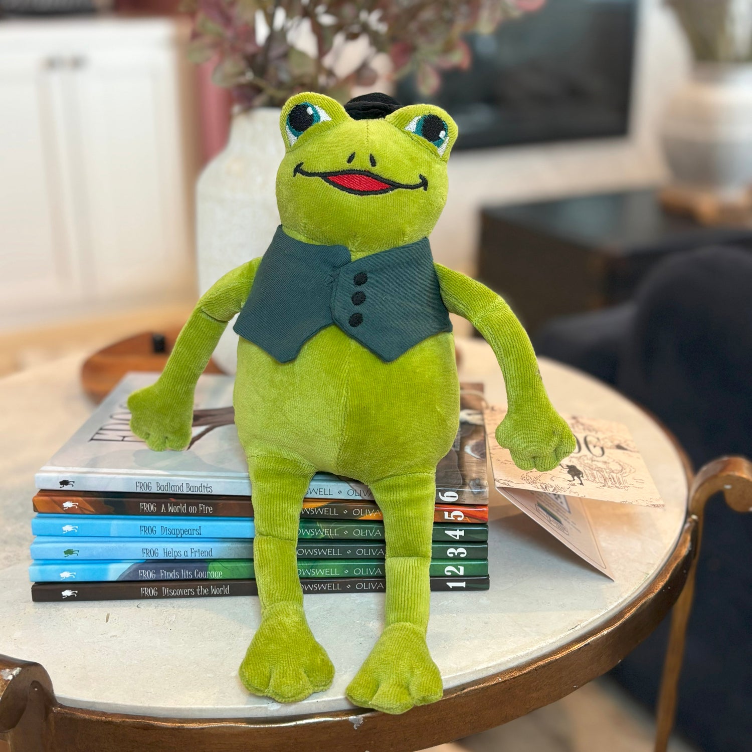Frog plushie on stack of children's books